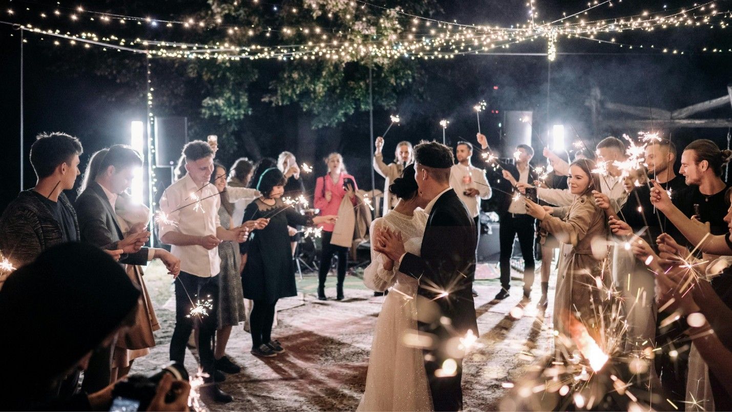 A wedding party holds sparklers around a dancing couple.