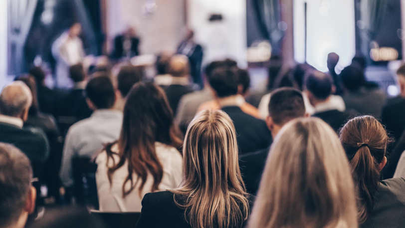 A seated crowd of professionals at a corporate conference.