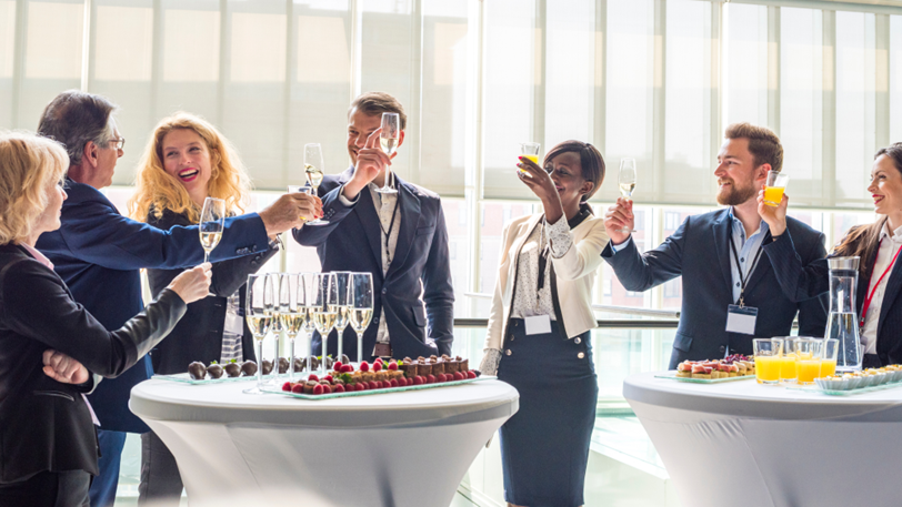Corporate co workers cheer with glasses of champagne at an event.