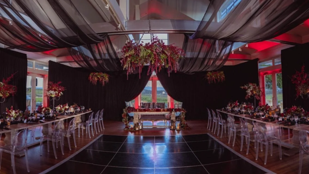A large ballroom set up with elaborate flowers and fabrics hanging from the ceiling.